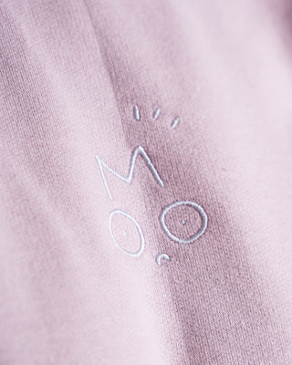 Close-up of a textured pink fabric with embroidered text on a pink OUT OF MOOD SIMPL crewneck fabric