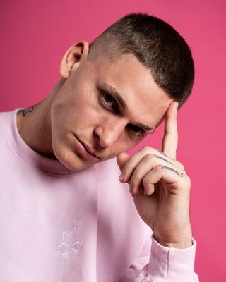 Man wearing a pink OUT OF MOOD SIMPL crewneck with a logo against a pink background