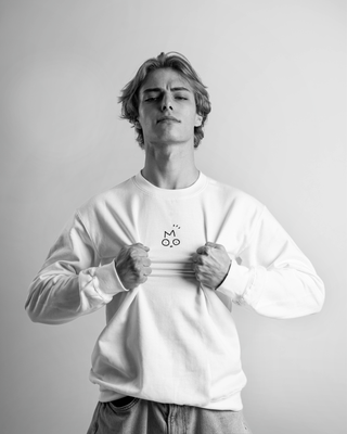 Person wearing a white OUT OF MOOD SIMPL crewneck with a logo on a plain background. Famous hungarian streetwear brand.